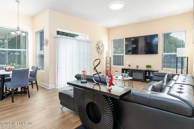living area featuring baseboards, a notable chandelier, and light wood-style flooring