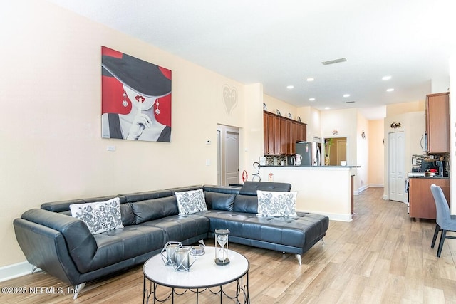 living area with baseboards, light wood-style flooring, and visible vents