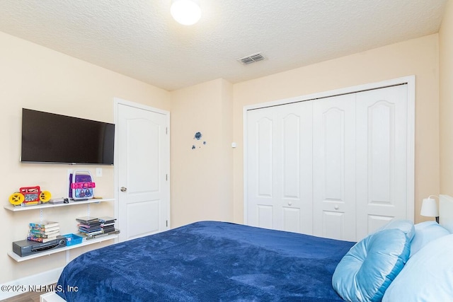 bedroom with a textured ceiling, visible vents, and a closet