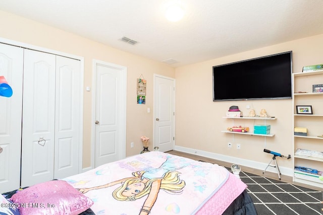 bedroom with visible vents, baseboards, dark wood finished floors, and a closet
