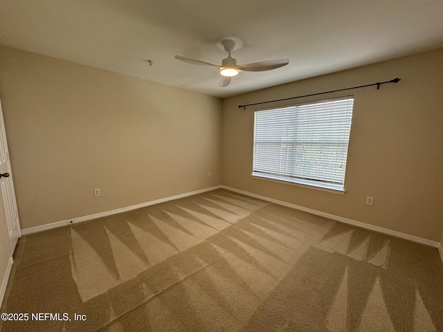 carpeted spare room featuring baseboards and ceiling fan