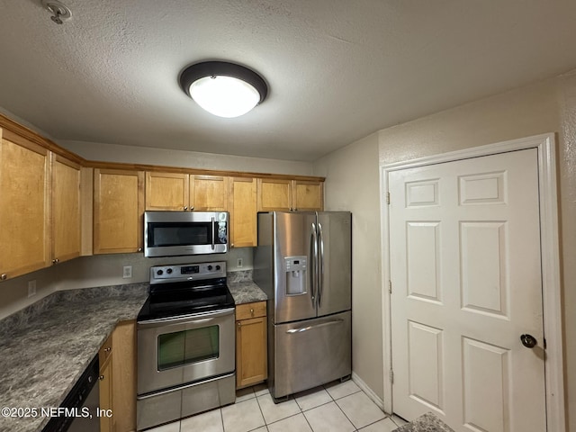 kitchen with dark countertops, appliances with stainless steel finishes, a textured ceiling, and light tile patterned flooring