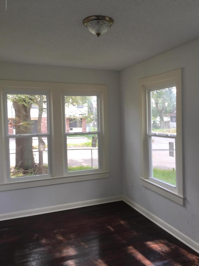 empty room featuring baseboards and dark wood-style floors