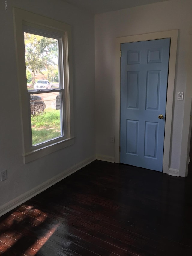 empty room featuring baseboards and dark wood-style floors