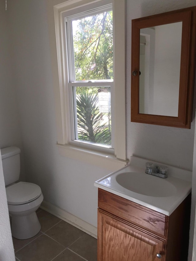 half bath with vanity, baseboards, tile patterned flooring, and toilet