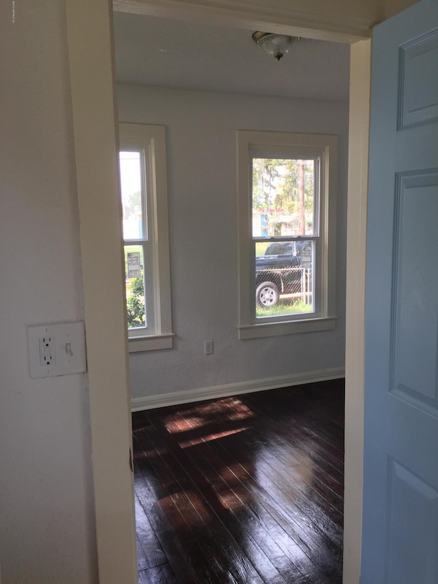 empty room with baseboards, plenty of natural light, and dark wood-style flooring