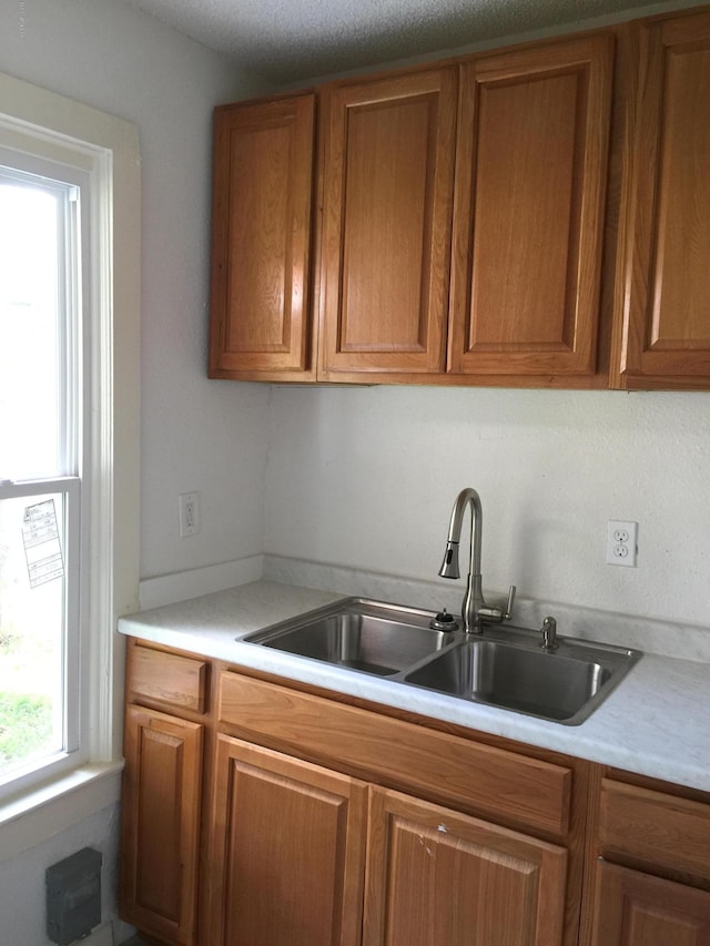 kitchen featuring a sink, light countertops, and brown cabinetry