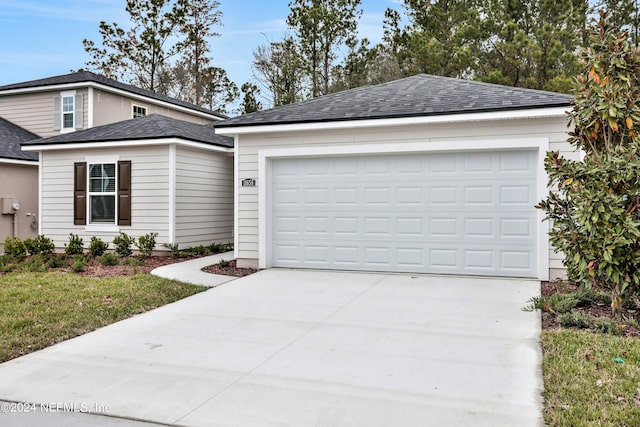 view of front of house featuring an attached garage, driveway, and roof with shingles