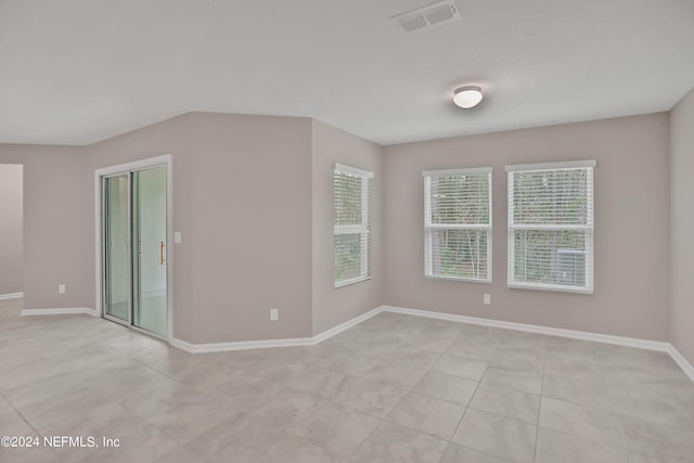 empty room with light tile patterned flooring, baseboards, and visible vents