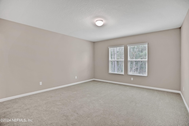 spare room featuring carpet flooring, a textured ceiling, and baseboards