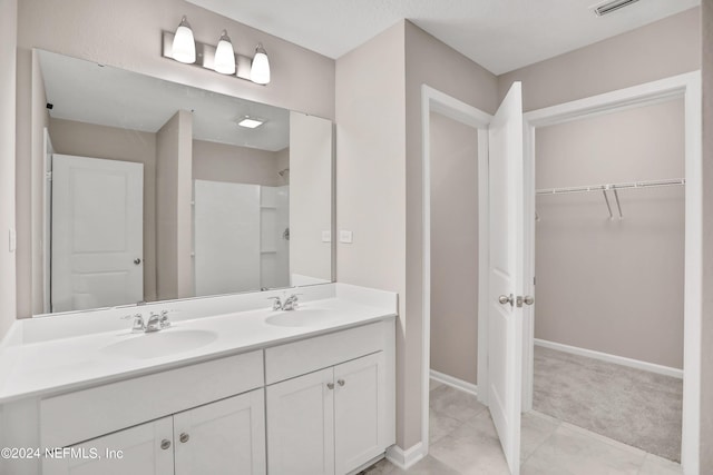 full bath with double vanity, a walk in closet, a sink, and a shower
