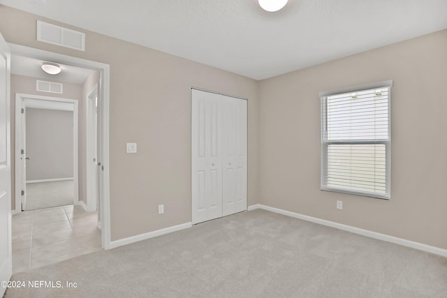 unfurnished bedroom with a closet, baseboards, light colored carpet, and visible vents
