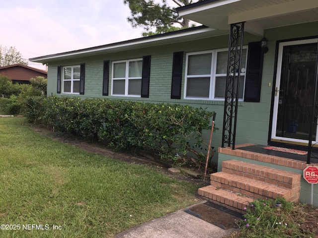 property entrance with brick siding and a yard