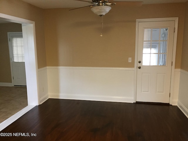 unfurnished dining area with baseboards, plenty of natural light, a ceiling fan, and dark wood-style flooring
