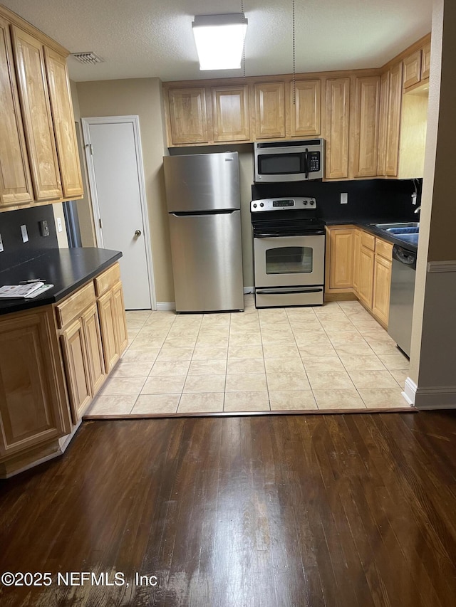 6938 Corkwood Rd, Jacksonville, FL 32277 - kitchen featuring appliances with stainless steel finishes, dark countertops, and light wood-style floors
