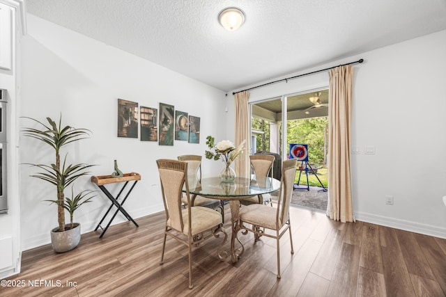 dining space with baseboards, a textured ceiling, and wood finished floors