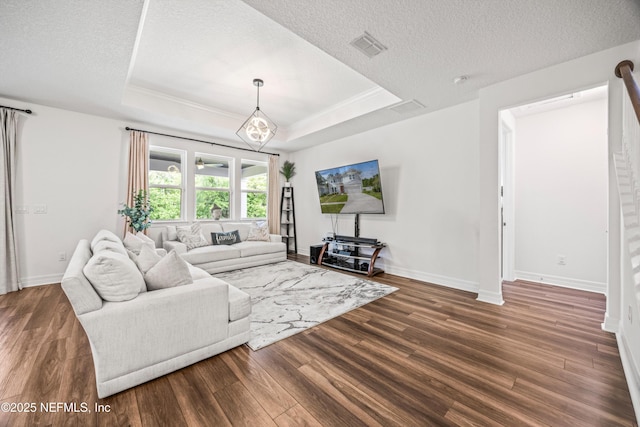 living room featuring baseboards, a textured ceiling, a tray ceiling, and wood finished floors