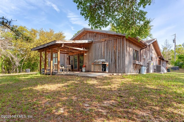 back of house with a patio, board and batten siding, a yard, and cooling unit