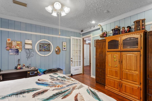 bedroom featuring ornamental molding, dark wood-style floors, a textured ceiling, and visible vents