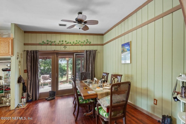 dining area featuring visible vents, ceiling fan, wood finished floors, and wooden walls