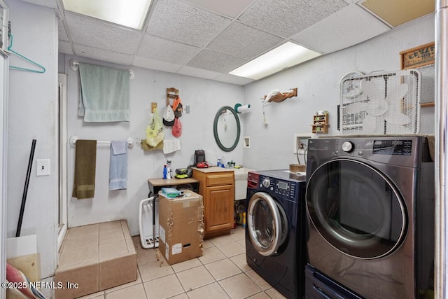 washroom with cabinet space, washing machine and dryer, and light tile patterned floors