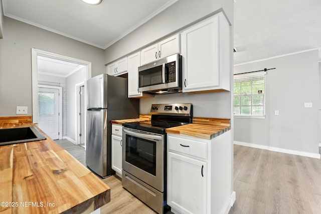 367 Orange Ave, Baldwin, FL 32234 - kitchen with ornamental molding, butcher block countertops, white cabinetry, light wood finished floors, and stainless steel appliances
