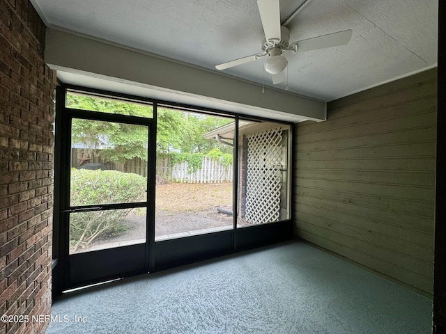 empty room featuring plenty of natural light, a ceiling fan, and brick wall