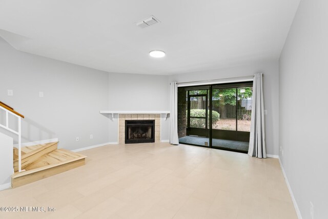 1909 University Blvd S Unit 204, Jacksonville, FL 32216 - unfurnished living room with baseboards, stairway, a tiled fireplace, and visible vents