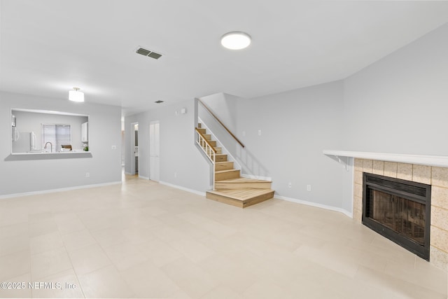 1909 University Blvd S Unit 204, Jacksonville, FL 32216 - unfurnished living room with baseboards, stairs, a tiled fireplace, and visible vents