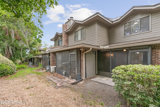 1909 University Blvd S Unit 204, Jacksonville, FL 32216 - rear view of property featuring a sunroom, cooling unit, a chimney, and brick siding