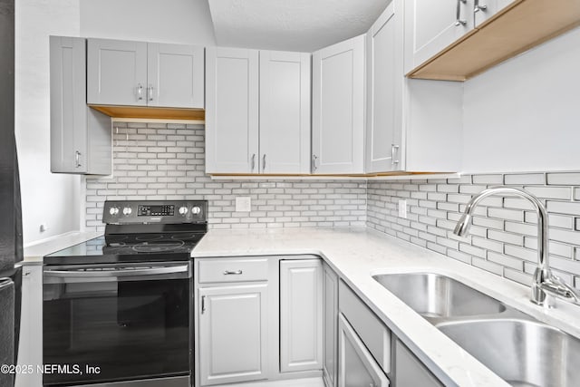 kitchen with a sink, decorative backsplash, stainless steel electric stove, and light stone countertops