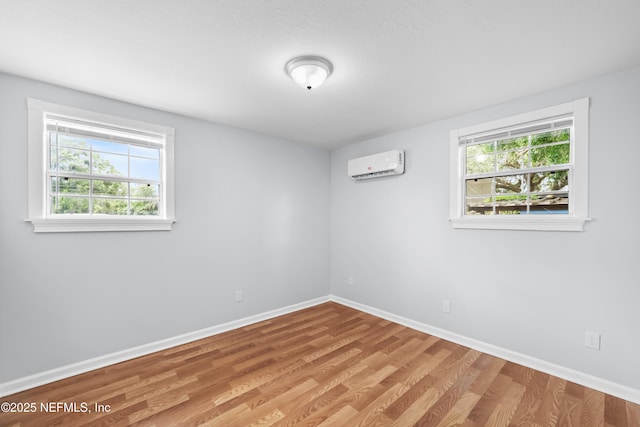 unfurnished room featuring baseboards, a wall mounted AC, and a healthy amount of sunlight