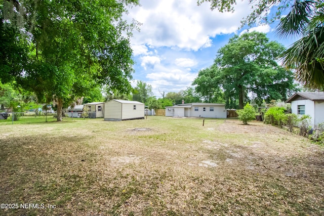 view of yard with an outdoor structure, a fenced backyard, and a storage shed