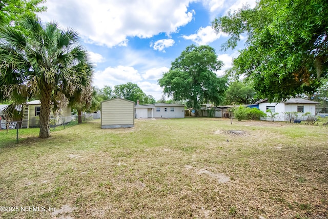 view of yard featuring fence, an outdoor structure, and a storage unit