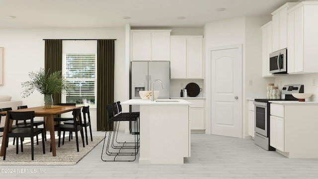 kitchen with white cabinets, a sink, light countertops, stainless steel appliances, and a kitchen bar