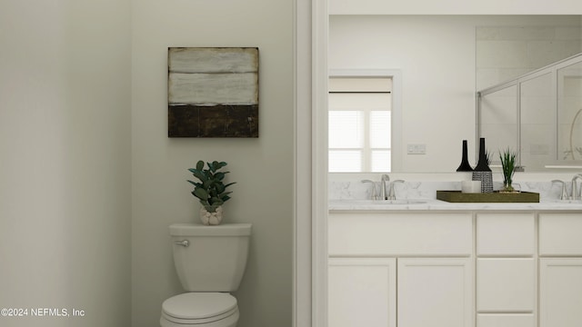bathroom with double vanity, toilet, and a sink