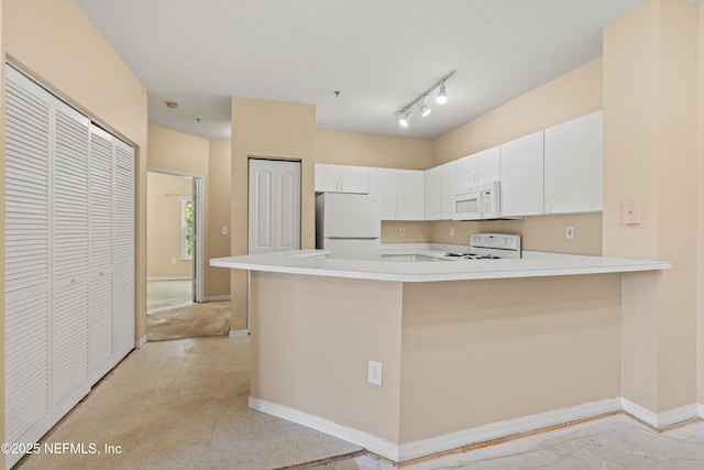 kitchen with light countertops, white cabinets, a peninsula, and white appliances