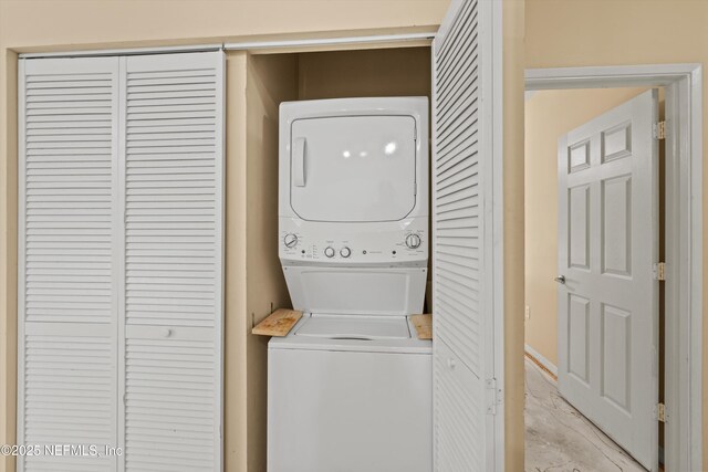 laundry area featuring stacked washing maching and dryer, baseboards, and laundry area