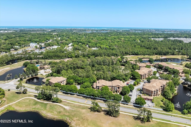 drone / aerial view with view of golf course, a water view, and a wooded view