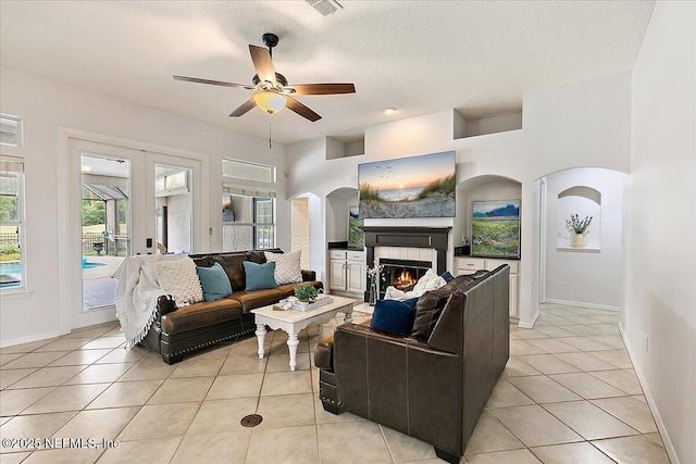 185 Edgewater Branch Dr, Saint Johns, FL 32259 - living area featuring light tile patterned flooring, a warm lit fireplace, ceiling fan, arched walkways, and baseboards