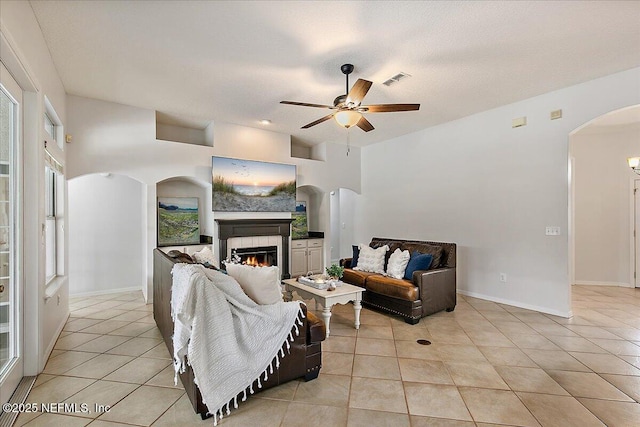 185 Edgewater Branch Dr, Saint Johns, FL 32259 - living area with a tiled fireplace, arched walkways, ceiling fan, and light tile patterned flooring