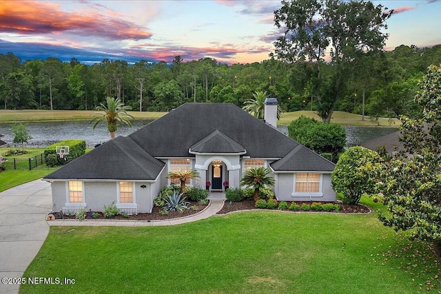 185 Edgewater Branch Dr, Saint Johns, FL 32259 - view of front of property featuring roof with shingles, stucco siding, a chimney, a lawn, and a water view