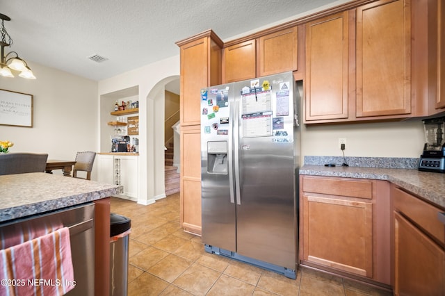 686 Reese Ave, Orange Park, FL 32065 - kitchen with visible vents, light tile patterned flooring, brown cabinets, arched walkways, and appliances with stainless steel finishes