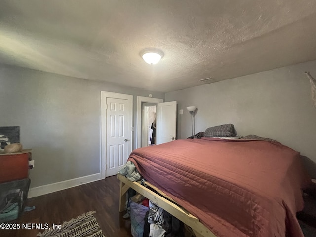 bedroom featuring a textured ceiling, baseboards, and dark wood-type flooring