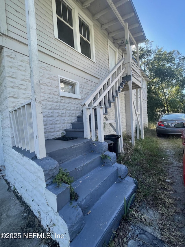 view of property exterior with stairway and stone siding