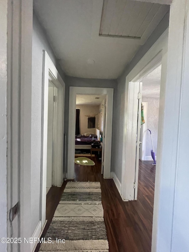 corridor featuring baseboards and dark wood finished floors