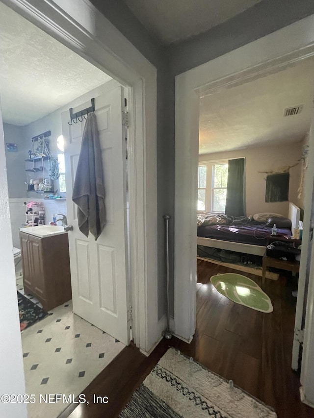 interior space with vanity, toilet, wood finished floors, and visible vents