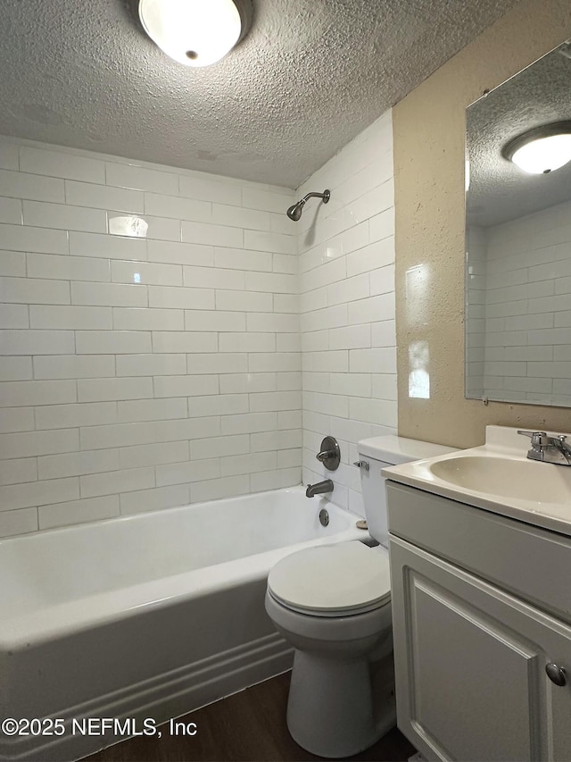 full bathroom with a textured ceiling, wood finished floors, vanity, toilet, and washtub / shower combination