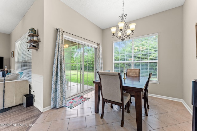 dining area featuring baseboards, light tile patterned floors, and a notable chandelier