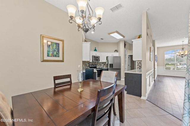 dining room featuring light tile patterned floors, visible vents, and a chandelier
